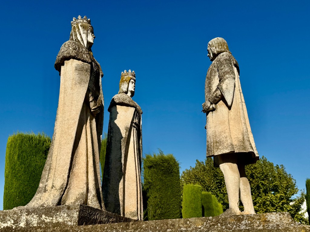 three tall statues in a garden