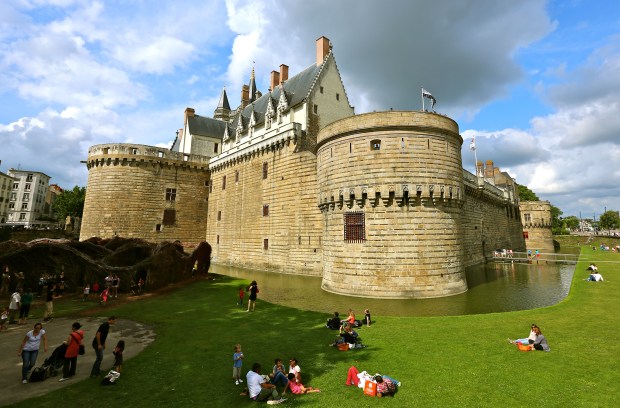 people relaxing on lawn outside of a castle