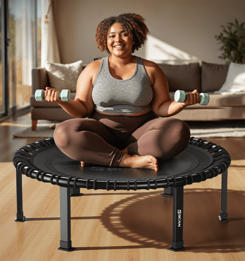 Woman with dumbbells sitting on fitness trampoline
